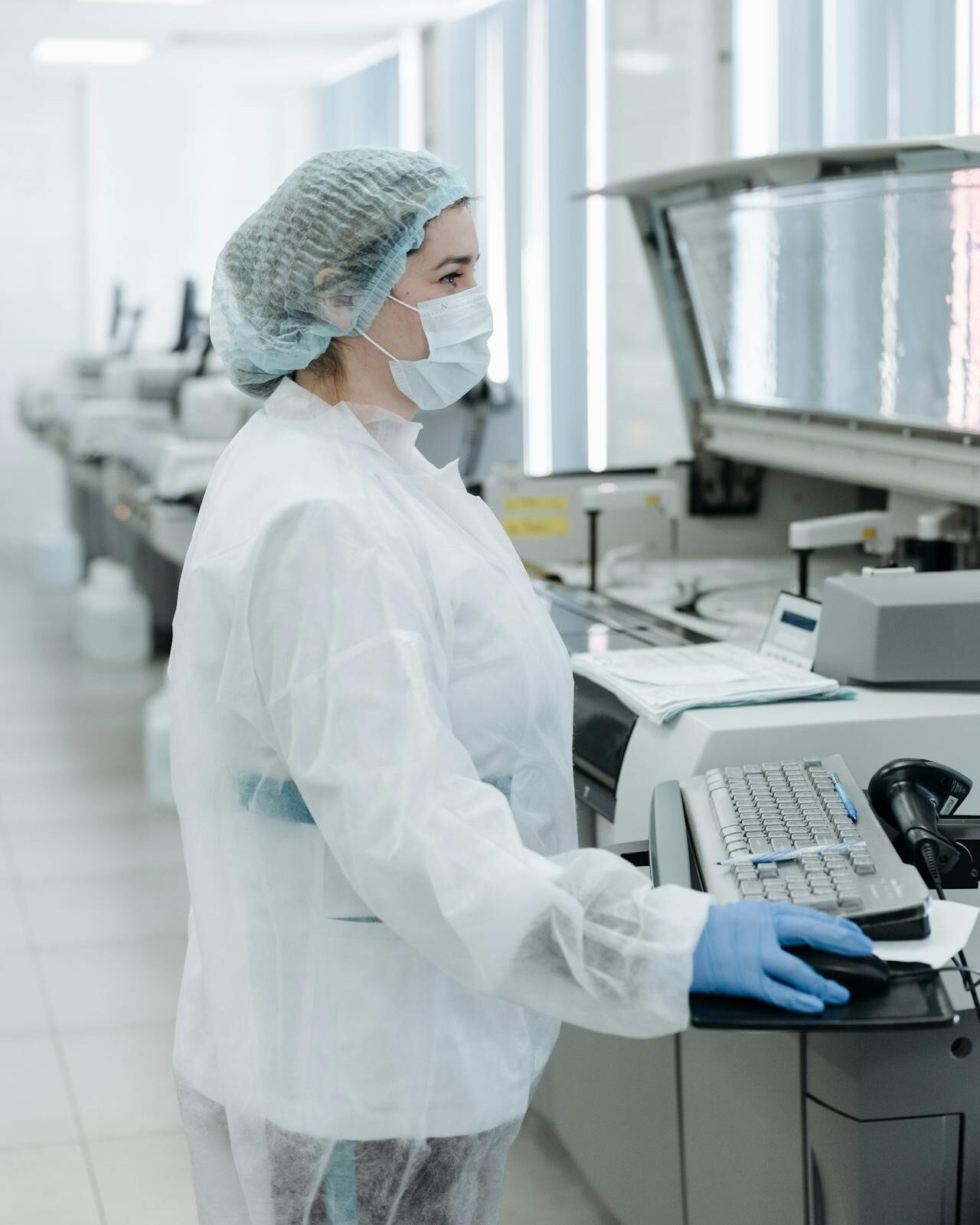 Pavel Danilyuk photographed lab technician in white protective suit, face mask, and blue gloves at a workstation in a clean, high-tech lab environment.
