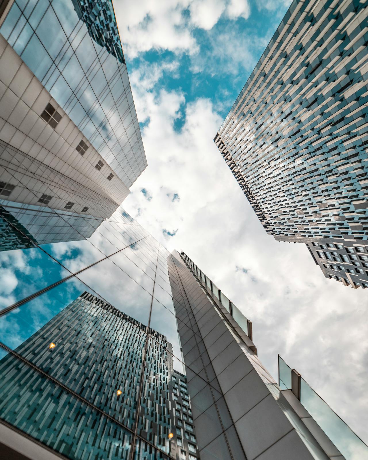 Tall glass office buildings rise in a city, reflecting a blue sky and modern architecture, conveying a corporate, professional environment suitable for business service pages.